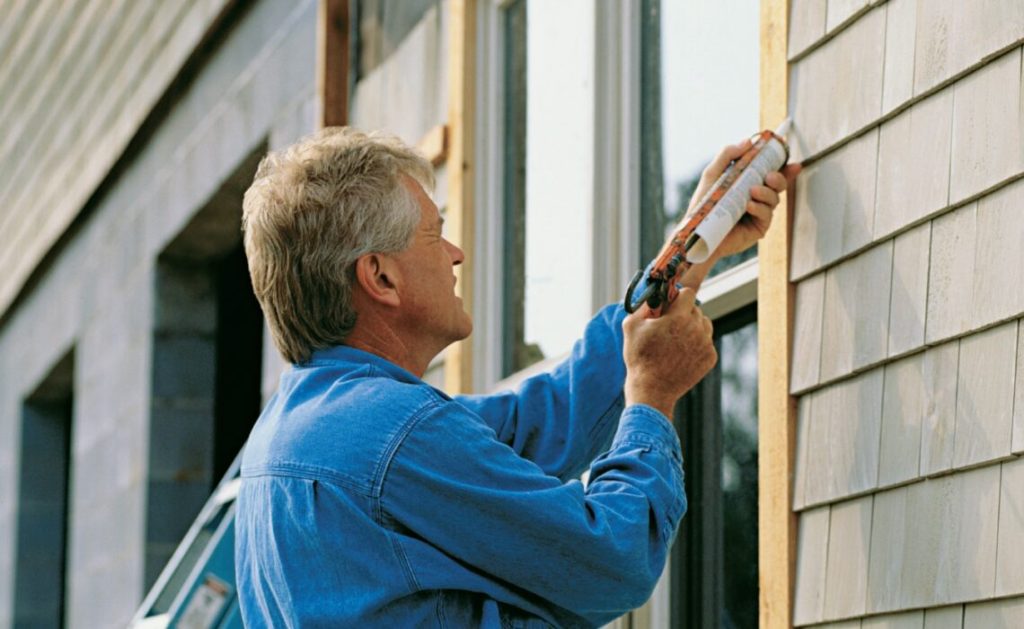 Hiring a House Painting Contractor: What You Should Know 3 Professional painter prepping exterior trim and siding before applying paint as part of a detailed house painting quote